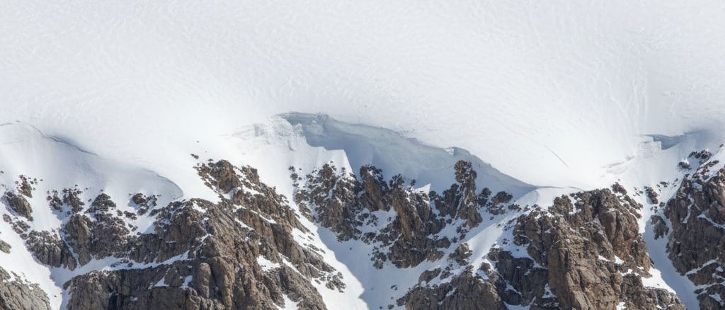 The line where snow ends on a mountain flank, rock below and white above